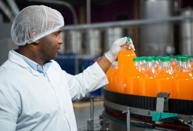 male-worker-checking-juice-bottles-factory_107420-96531