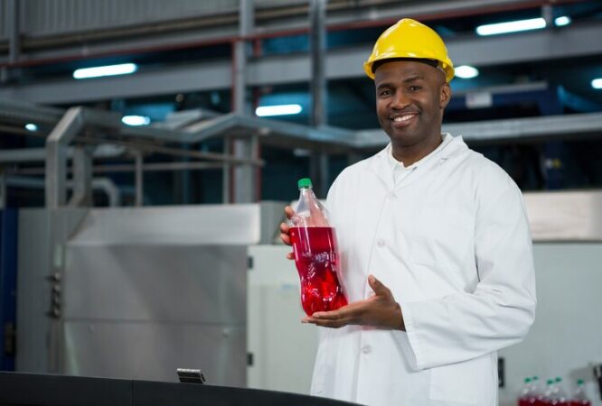 male-worker-showing-juice-bottle-factory_107420-96061