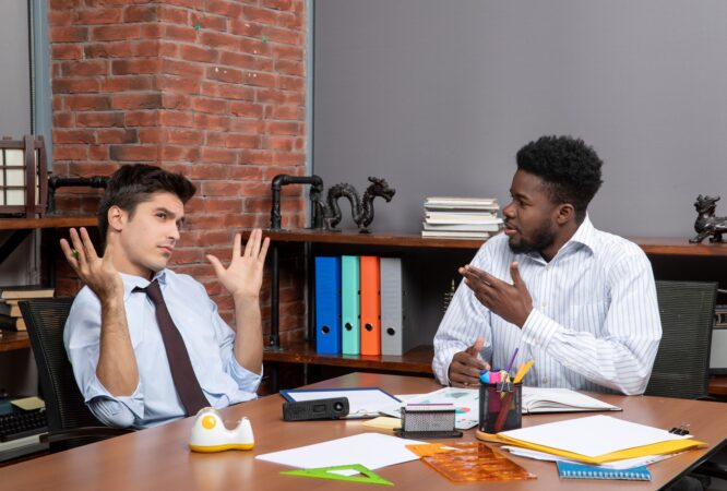 front-view-two-hardworking-businessmen-formal-wear-sitting-table-with-office-stuffs_140725-109556