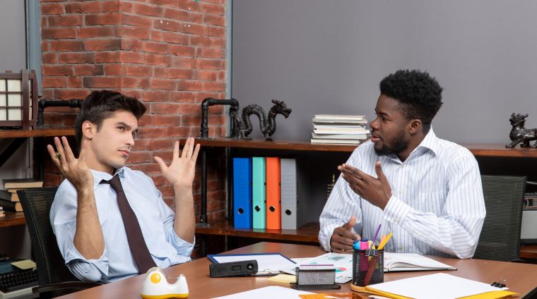 front-view-two-hardworking-businessmen-formal-wear-sitting-table-with-office-stuffs_140725-109556