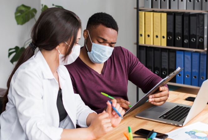 two-workers-office-pandemic-wearing-medical-masks_23-2148666364