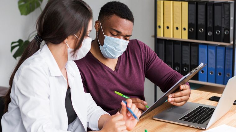 two-workers-office-pandemic-wearing-medical-masks_23-2148666364