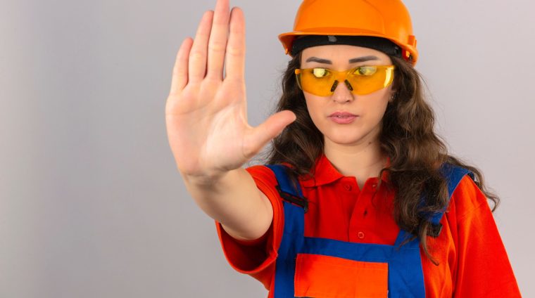 young-builder-woman-construction-uniform-yellow-glasses-safety-helmet-doing-stop-sing-with-palm-hand-warning-expression-isolated-white-wall_141793-16274